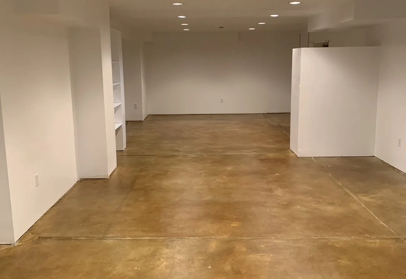 Tan stained and sealed concrete floor in a finished basement with white walls